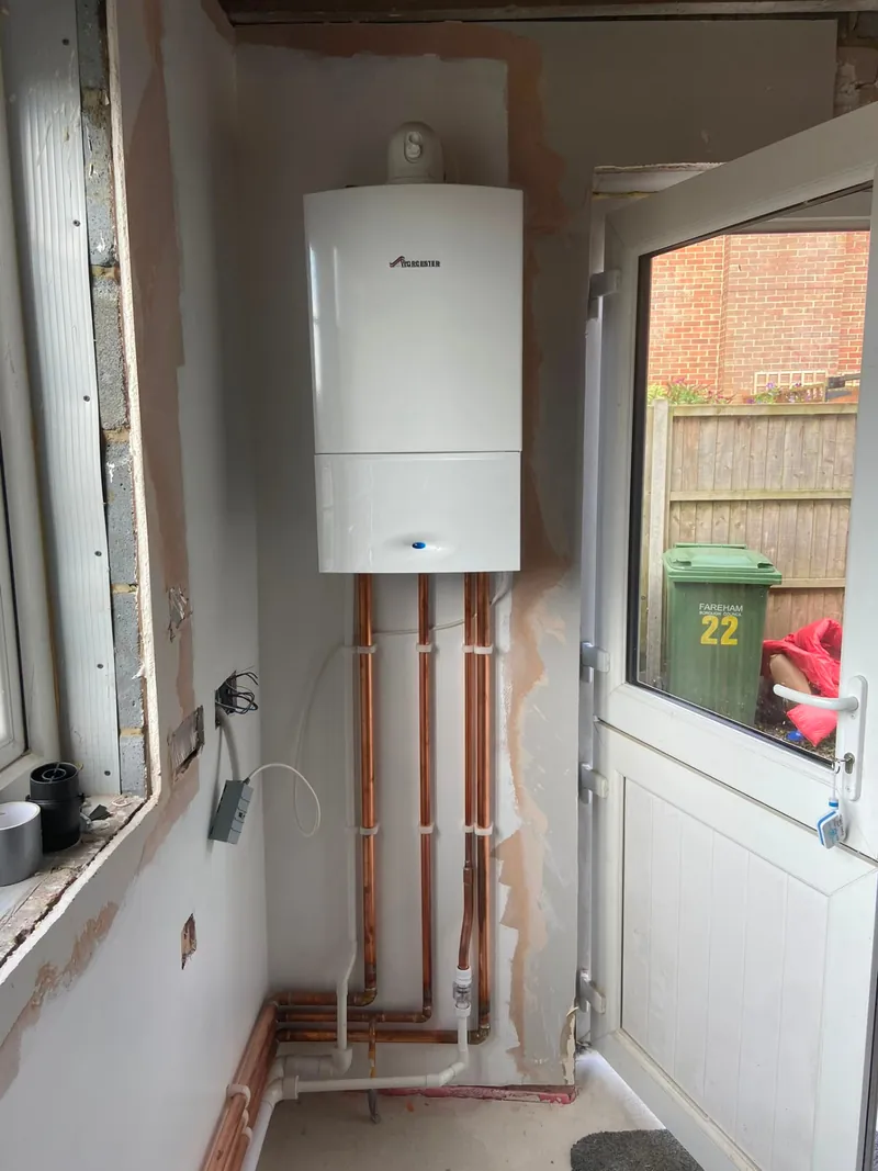 Worcester boiler fitted beside a glazed door with copper pipework