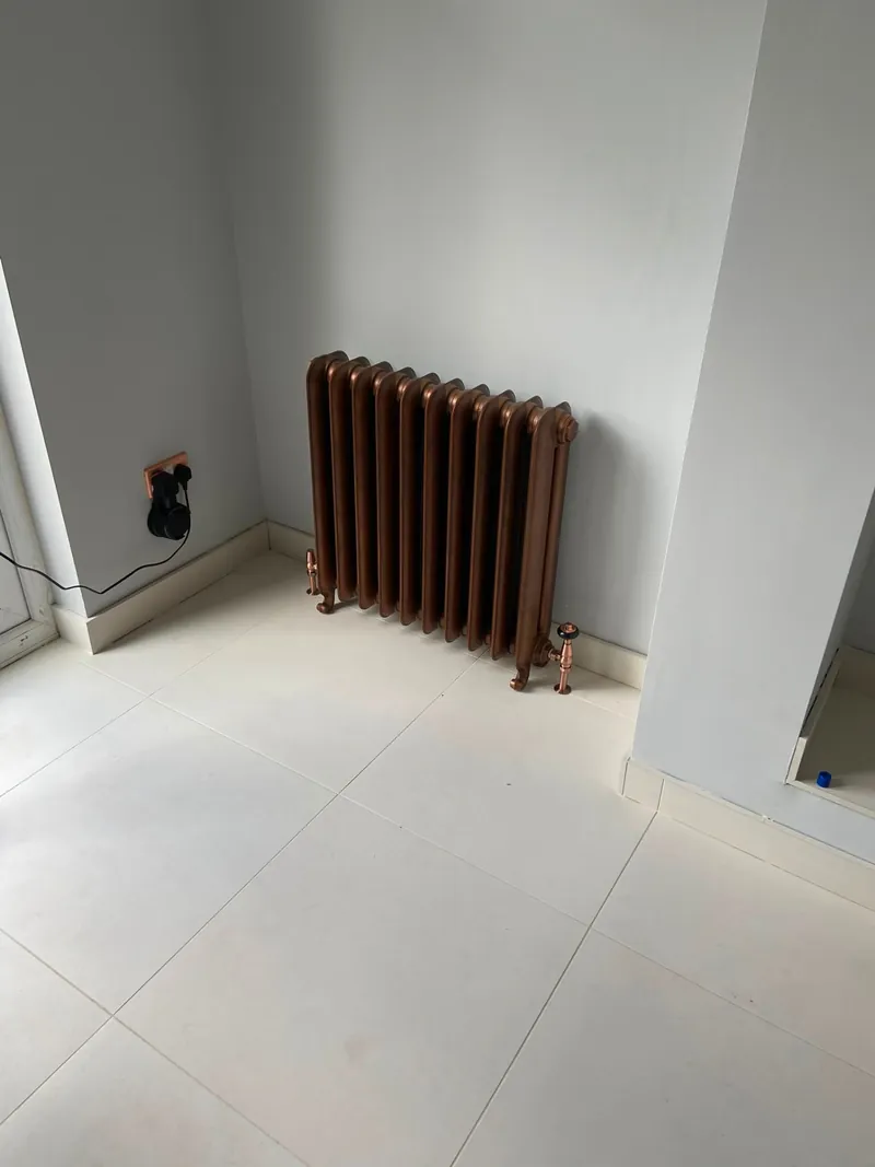 Dark column radiator installed on a tiled floor