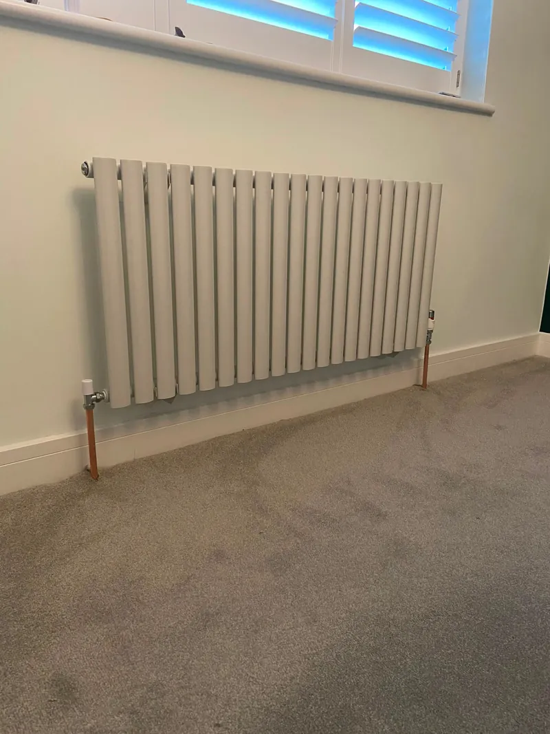 White vertical radiator installed beneath a window